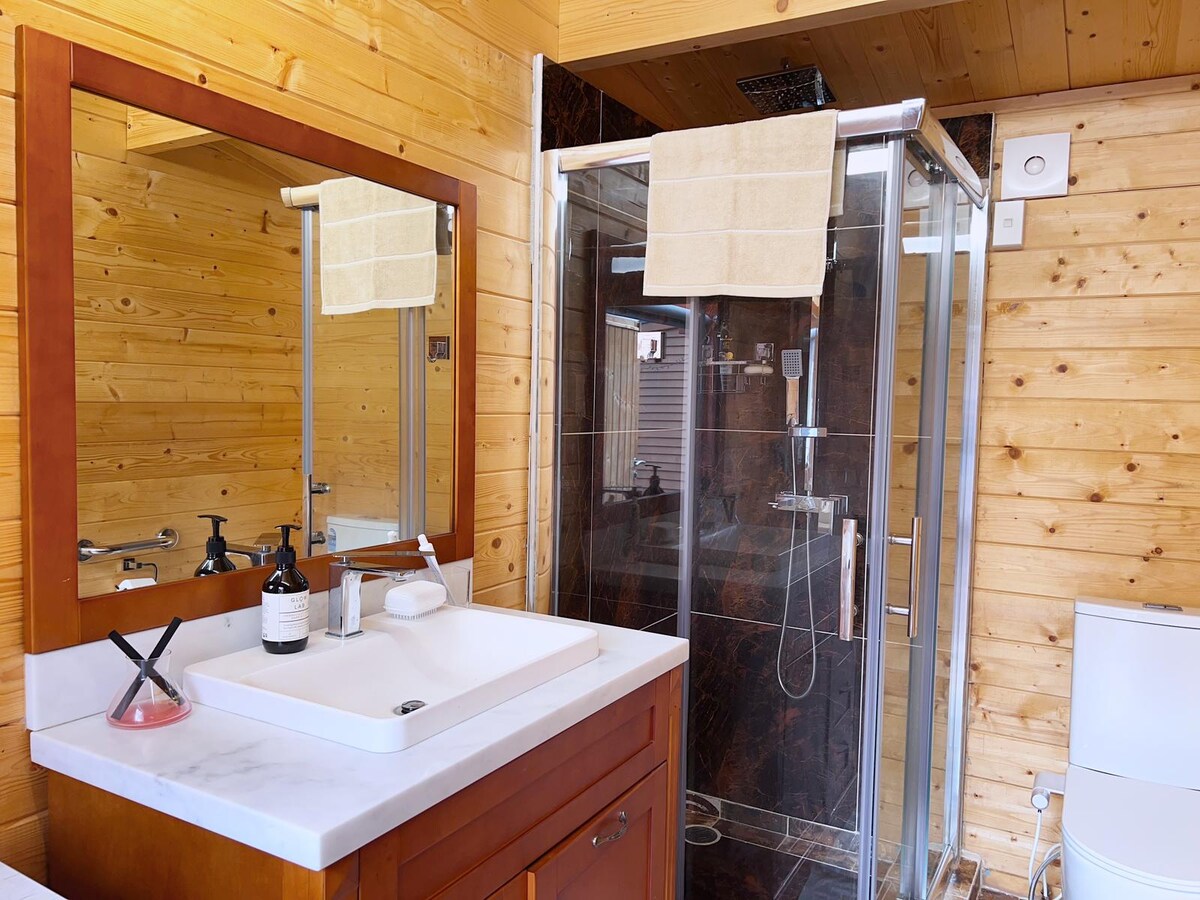The bathroom at Auckland Airport Cabin, with a rain shower and timber-lined walls.