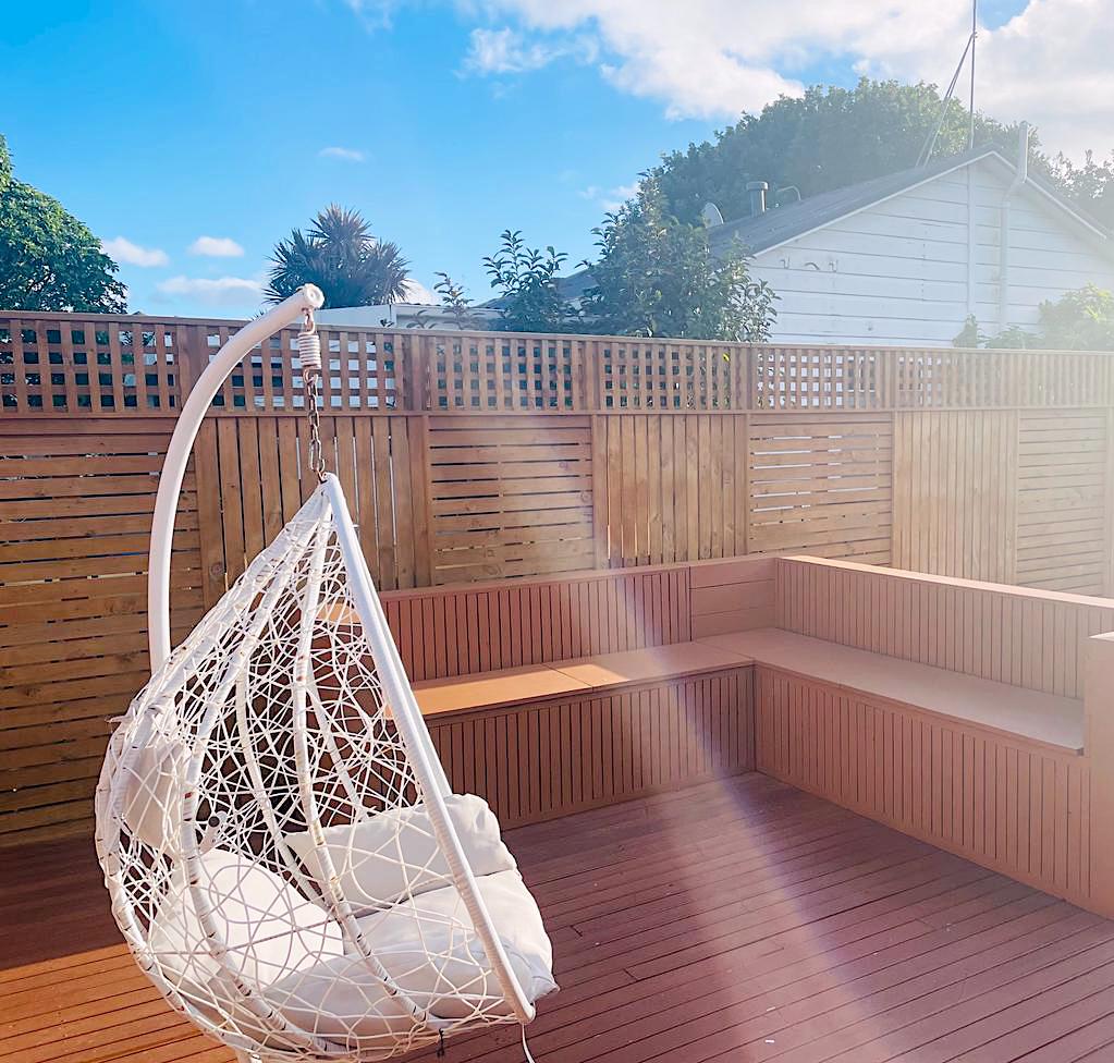 A hanging egg chair in a sunlit corner of the deck at Auckland Airport Cabin.