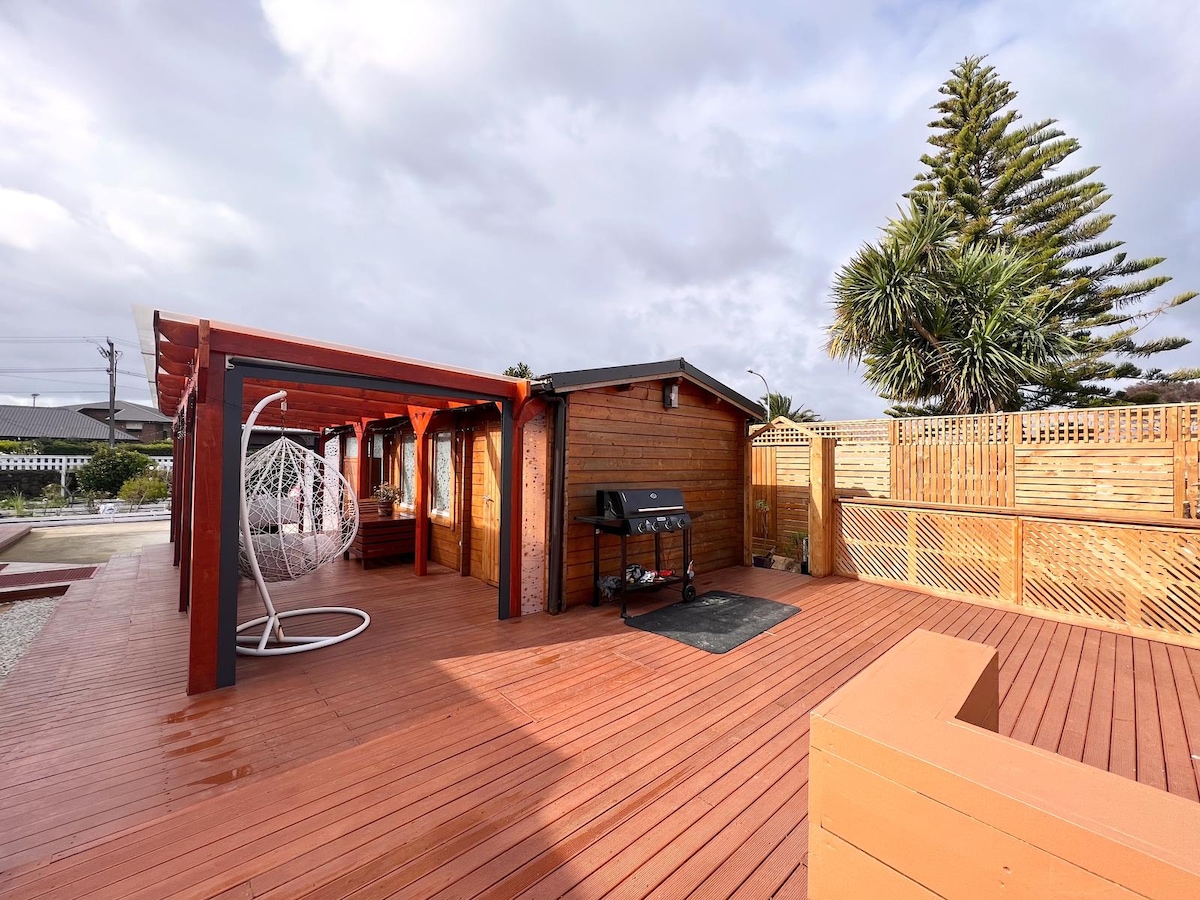 The private outdoor deck with barbecue, pergola and hanging chair at Auckland Airport Cabin.